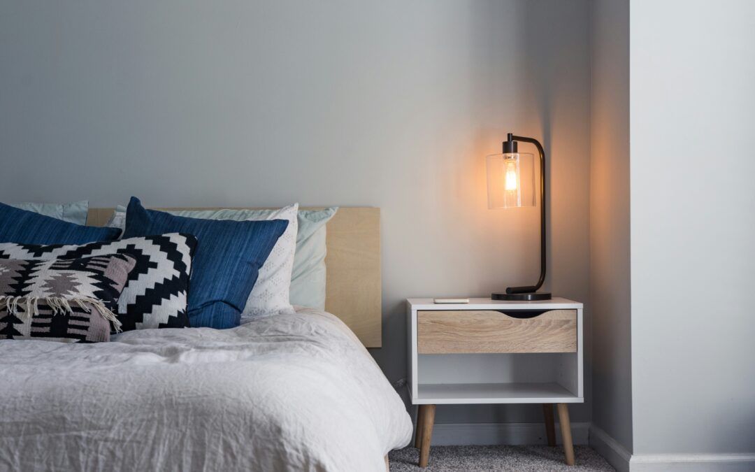 Symbolbild für Tinnitus und Schlaf: ruhiges Schlafzimmer mit Nachttisch, sanfter Beleuchtung und aufgeräumtem Bett für eine entspannte Schlafumgebung